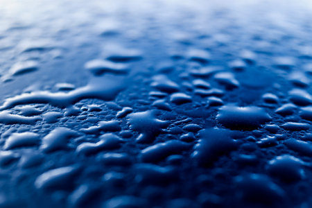 Condensed dewdrops on the smooth blue surface of a metallic car.の写真素材