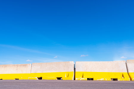 Detail of temporary concrete barricade walls on a newly paved road, with blue sky and copy space.の写真素材