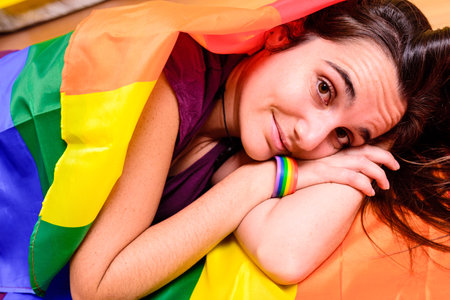 Young woman rolled up in a gay pride flag.
