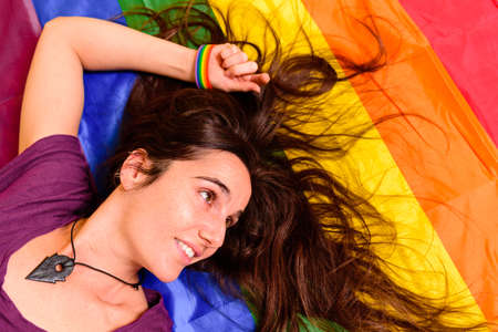 Young student girl lying on a gay flag viewed from above.の写真素材