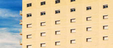 Long residential building with a repeat in brick wall pattern, with blue sky in the background