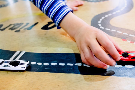 Child plays with two miniature cars in a toy circuit.の写真素材