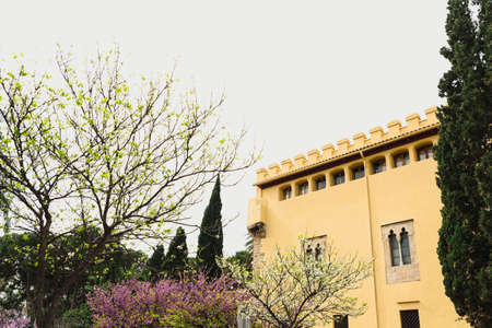 Facade of a secluded modern monastery with fences seen among the pretty trees in blossom.の写真素材