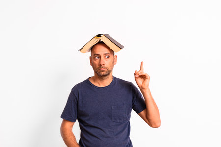 Funny man with an open book on his head thinks and has ideas.の写真素材
