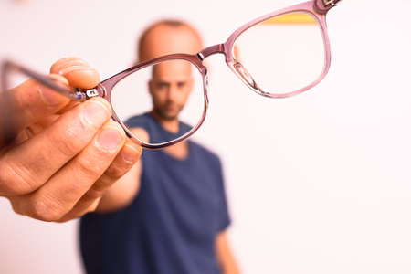Mature man holds astigmatism glasses with plastic polymer lenses.の写真素材