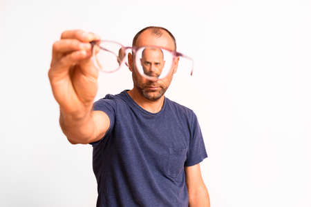 Myopia in mature men is corrected with glasses, a young man holds glasses in his hand.