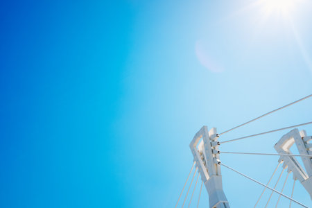 Blue sky ripped into a corner by the top of a modern metal bridge frame.