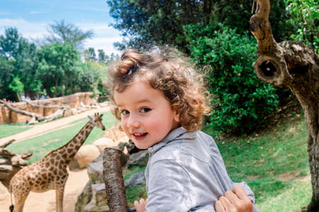 Happy girl on her first visit to a zoo visiting giraffes