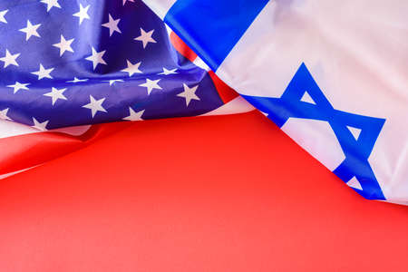 International treaty of collaboration between the countries of Israel and the United States, flags on red background.の写真素材