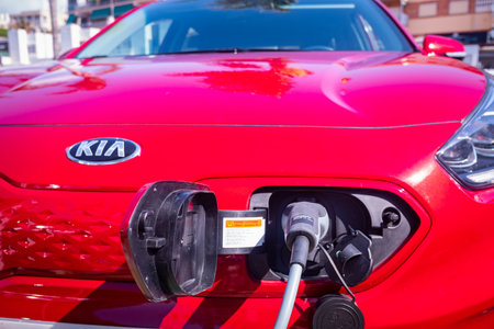 Valencia, Spain - July 6, 2021: Red car recharging its lithium electric batteries at a free public station.のeditorial素材