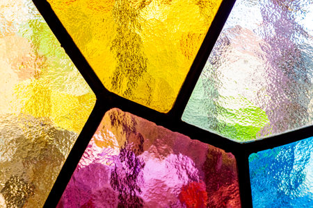 Detail of a multicolored mosaic of translucent colors in the stained glass of a church window.