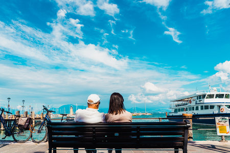 Verona, Italy - September 21, 2021: A retired couple rest on a bench as they relax on the shore of a harbor on an Italian lake.のeditorial素材