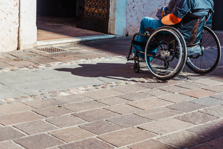 Rome, italy - september 22, 2021: A person in a wheelchair faces a step at the entrance of an unadapted building.のeditorial素材