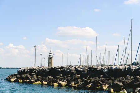 Lighthouse along a breakwater in the Italian port of Lake Garda.の写真素材