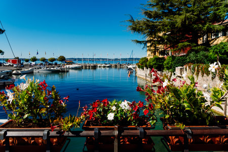 Sirmione, Italy - September 28, 2021: Boats moored next to Sirmione Castle on Lake Garda admired by tourists in summer.のeditorial素材