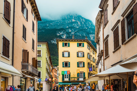 Riva del garda, italy - october 2, 2021: Tourists relax on the terraces of the bars of the touristy village near the alps.のeditorial素材