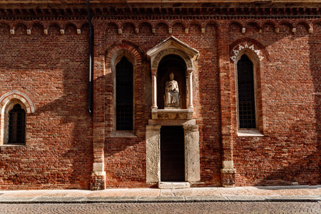 Brick facade in the afternoon sun of a religious Veronese hermitage with a statue of a saint.の写真素材