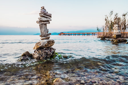 Small mountains of stones in columns created by tourists on the shore of a lake at sunset.の写真素材
