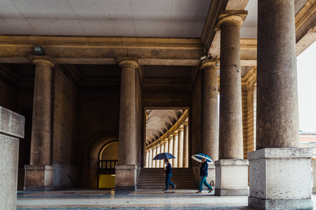 People walk with umbrellas on a rainy day through a cemetery.のeditorial素材