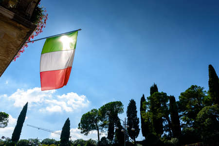 The Italian flag flutters against the sun on a decrepit Italian political building, copy space.の写真素材