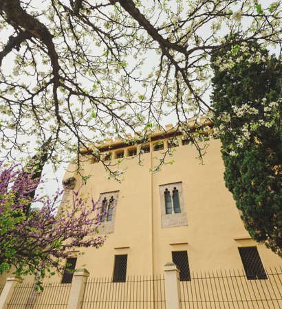 Facade of a secluded modern monastery with fences seen among the pretty trees in blossom.の写真素材