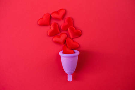Metaphor of female menstrual cup collecting menstruation blood, isolated on red background.の写真素材