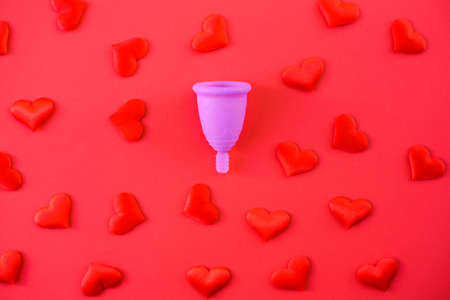 Metaphor of female menstrual cup collecting menstruation blood, isolated on red background.の写真素材