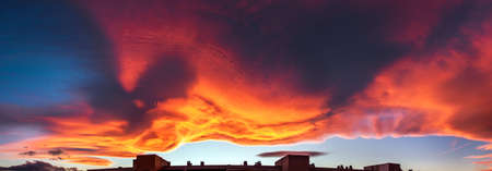 A large cloud with curious wavy shapes and warm reddish colors during a sunset sky background.