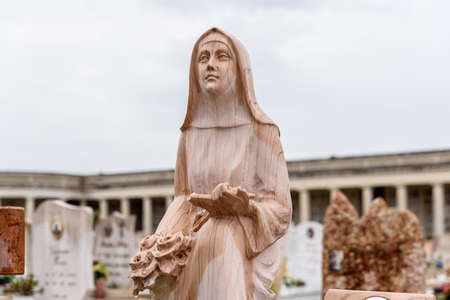 Marble sculpture of a caring virgin near graves in a Christian cemetery.の写真素材