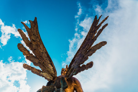 A sculpture of an angel, rear view of its wings against the sky.のeditorial素材