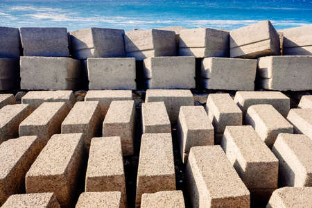 Stone blocks on a seawall of a port breakwater on the Atlantic coast on a sunny day.