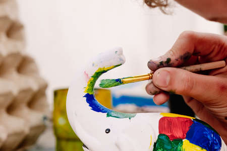 Child plays to unleash his creativity by decorating a white plaster figure with colored paints, during the summer holidays.の写真素材