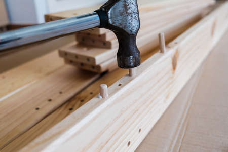 Wooden boards with wooden nails to join a piece of furniture with a hammer.の写真素材