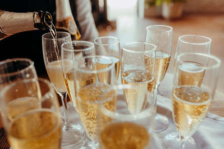 Champagne glasses filled by a waiter to celebrate good news with alcohol.の写真素材