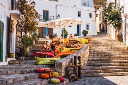 Ibiza, spain - july 25, 2022: Young tourists enjoy some drinks on the terrace of a bar in the old town of Ibiza.のeditorial素材