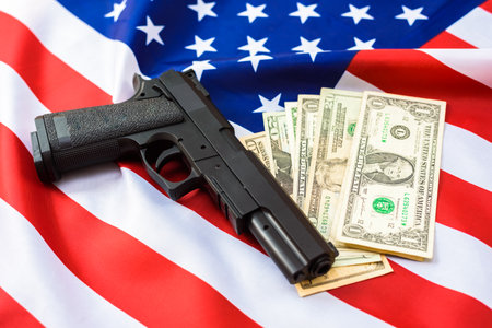 Gun over American flag with dollar bills around it.の写真素材