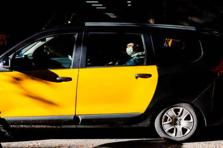 Barcelona, Spain - December 12, 2022: A person wearing a face mask travels inside a taxi in the...