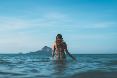 A beautiful young woman wades into the sea for a swim.の素材
