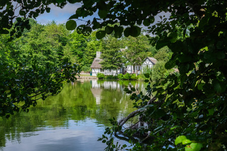 Beautiful and appealing cottage by a lake, seen through tree leaves.