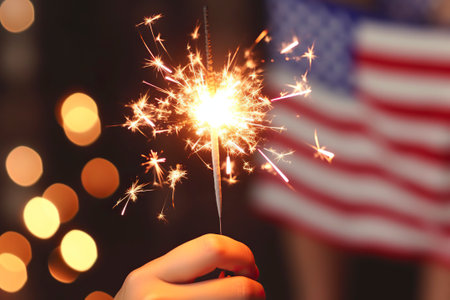 Young man holds a sparkler in his hand, celebrating an American patriotic event.の素材