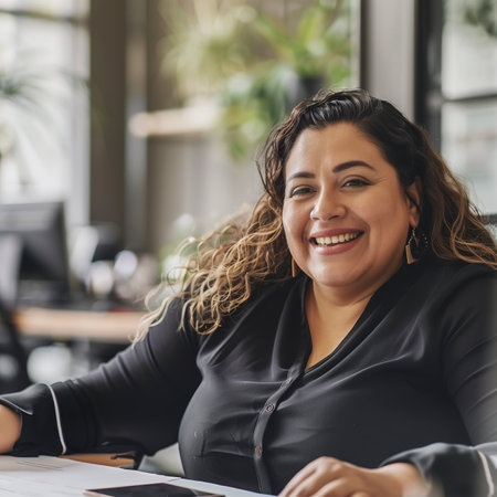 Chubby Hispanic woman sitting at table, focused on her laptop screen.の素材