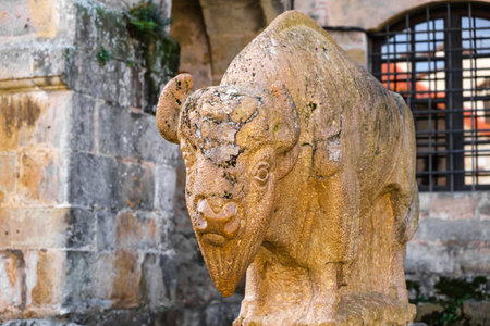 A stone statue of a bull stands prominently in front of a historic building in the medieval city of Santillana del Mar. The bull statue exudes strength and power, adding a sense of grandeur to the architectural setting.の写真素材