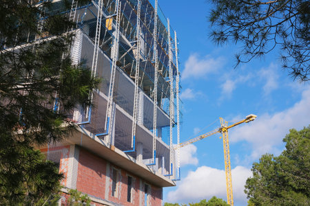 Construction site with cranes and building under construction against blue sky.