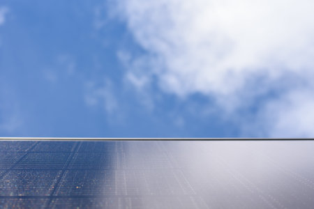 A solar panel is positioned below a bright blue sky with clouds. The scene emphasizes the solar...
