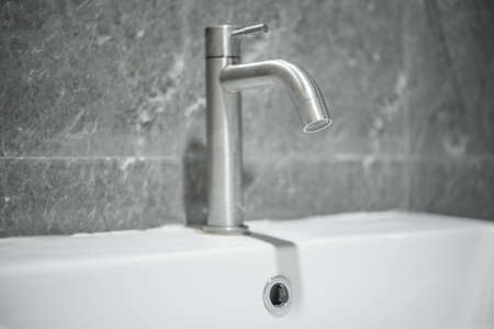A tap or faucet on a white washbasin.Save water campaign.の写真素材