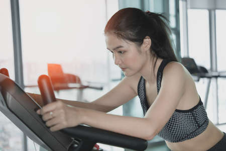 Asian girl in sportswear cycling on exercise bike.
