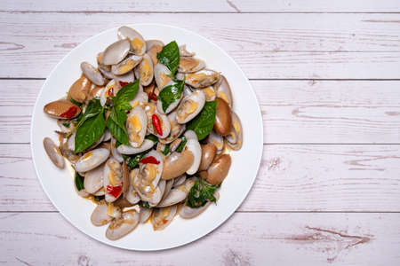 Stir fried Clams with roasted chili paste in white dish on the white wood table.の写真素材