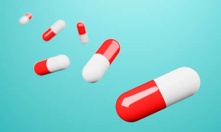 Red and white capsules on cyan green background.の写真素材