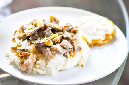 Fried sliced pork with garlic and fried egg,Fried Pork with Garlic Pepper on Riceの写真素材