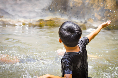 a boy at the waterfallの写真素材